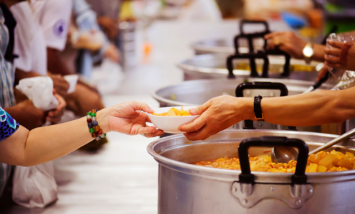 A hand is offering a plate of food to another hand.